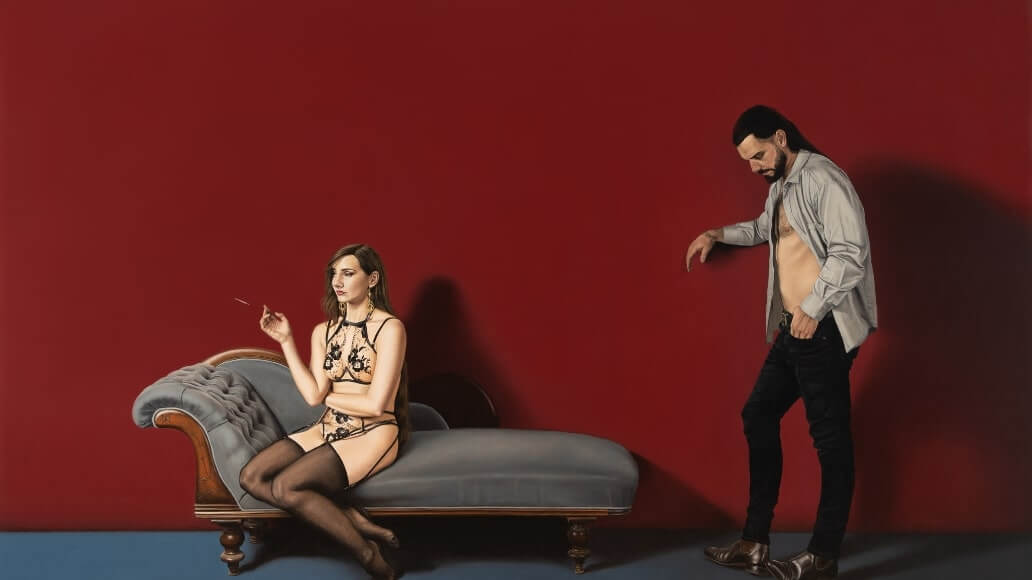 A woman in lingerie sits on a chaise lounge, holding a cigarette. A man with an open shirt stands beside her. The background is a deep red wall.