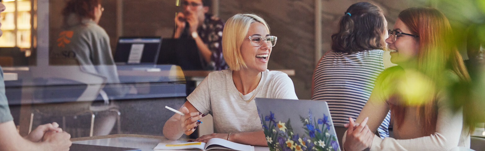 Students sitting at a desk smiling 