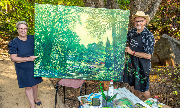 Vice-chancellor standing with artist and his artwork.