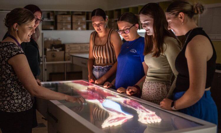 students gather around a technological table