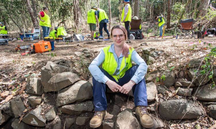 woman sitting in bush with workers around her 