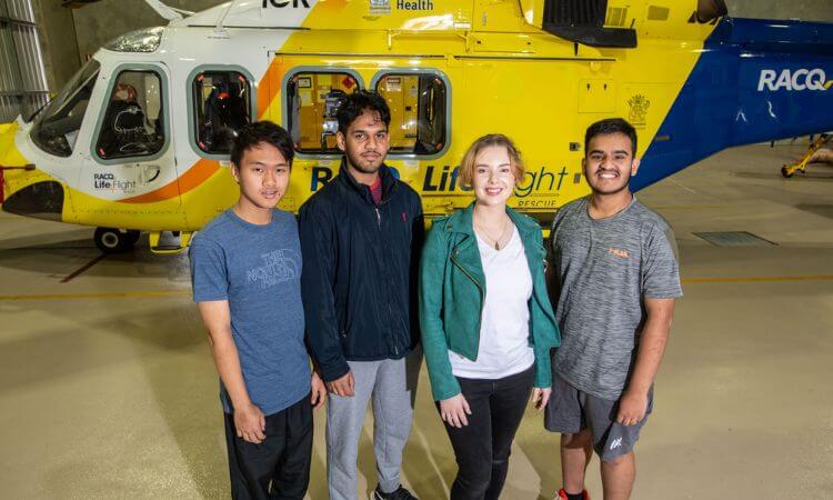 students in front of a yellow helicopter