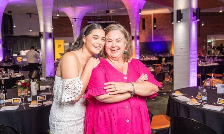 two women standing and smiling 