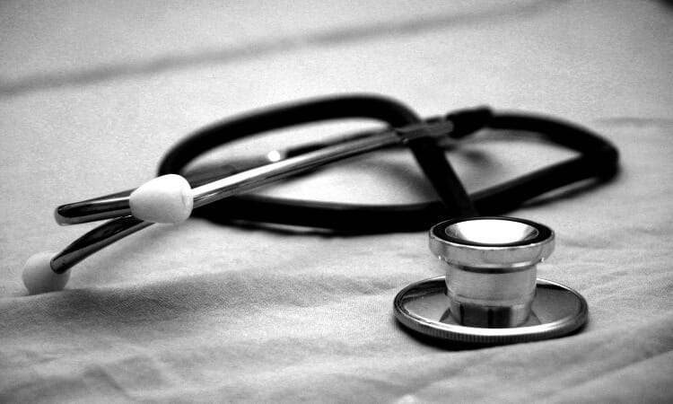 A black and white stethoscope lies on a fabric surface, with the earpieces and diaphragm visible.