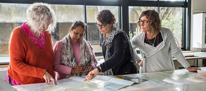 Four female UniSQ lecturers looking at map of Aboriginal land areas